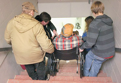 Volunteers carrying wheelchair down stairs